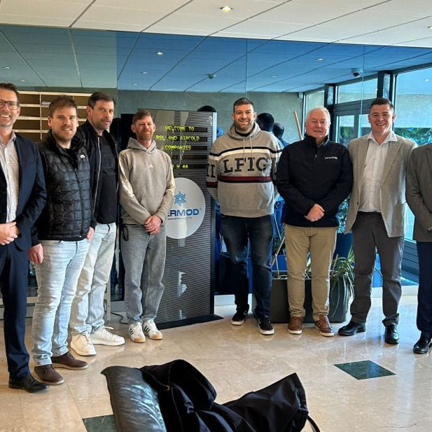 Group of men posing for a photo in an indoor setting with a branded Fermod backdrop