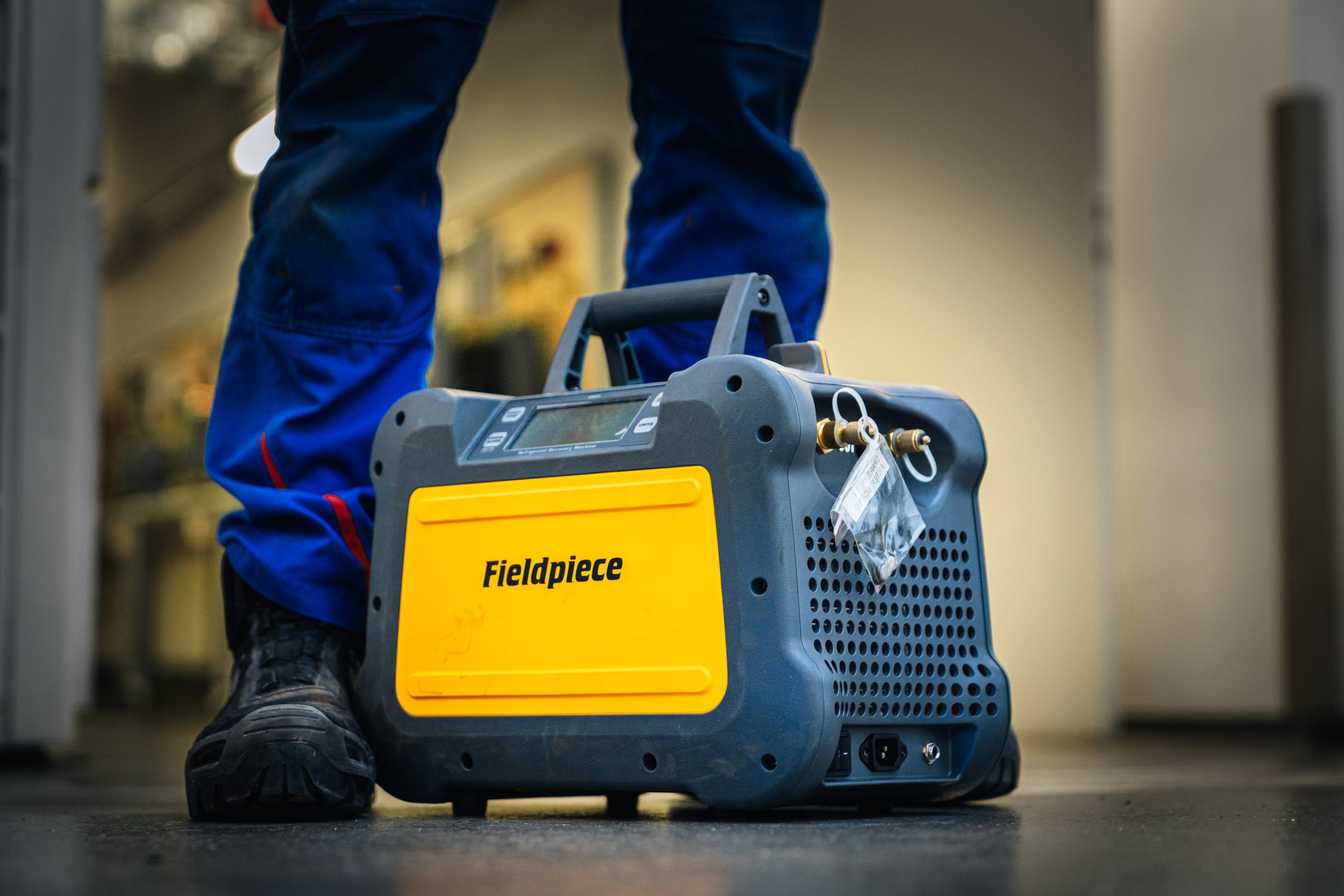 Fieldpiece portable device on a floor with a technician wearing blue trousers in the background