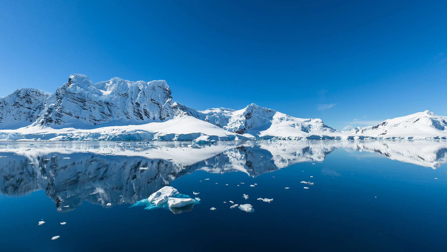 Frozen landscape with snow-covered mountains and clear blue sky