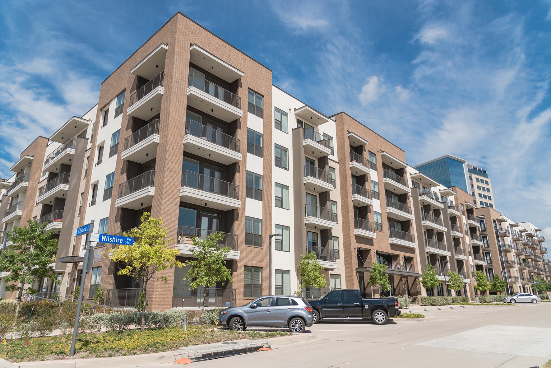 Multistory apartment building with cars parked in front on a clear day