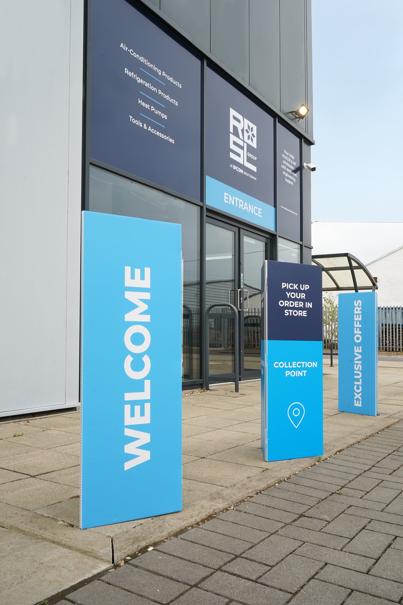 Blue welcome signs in front of a building with signage on the wall.
