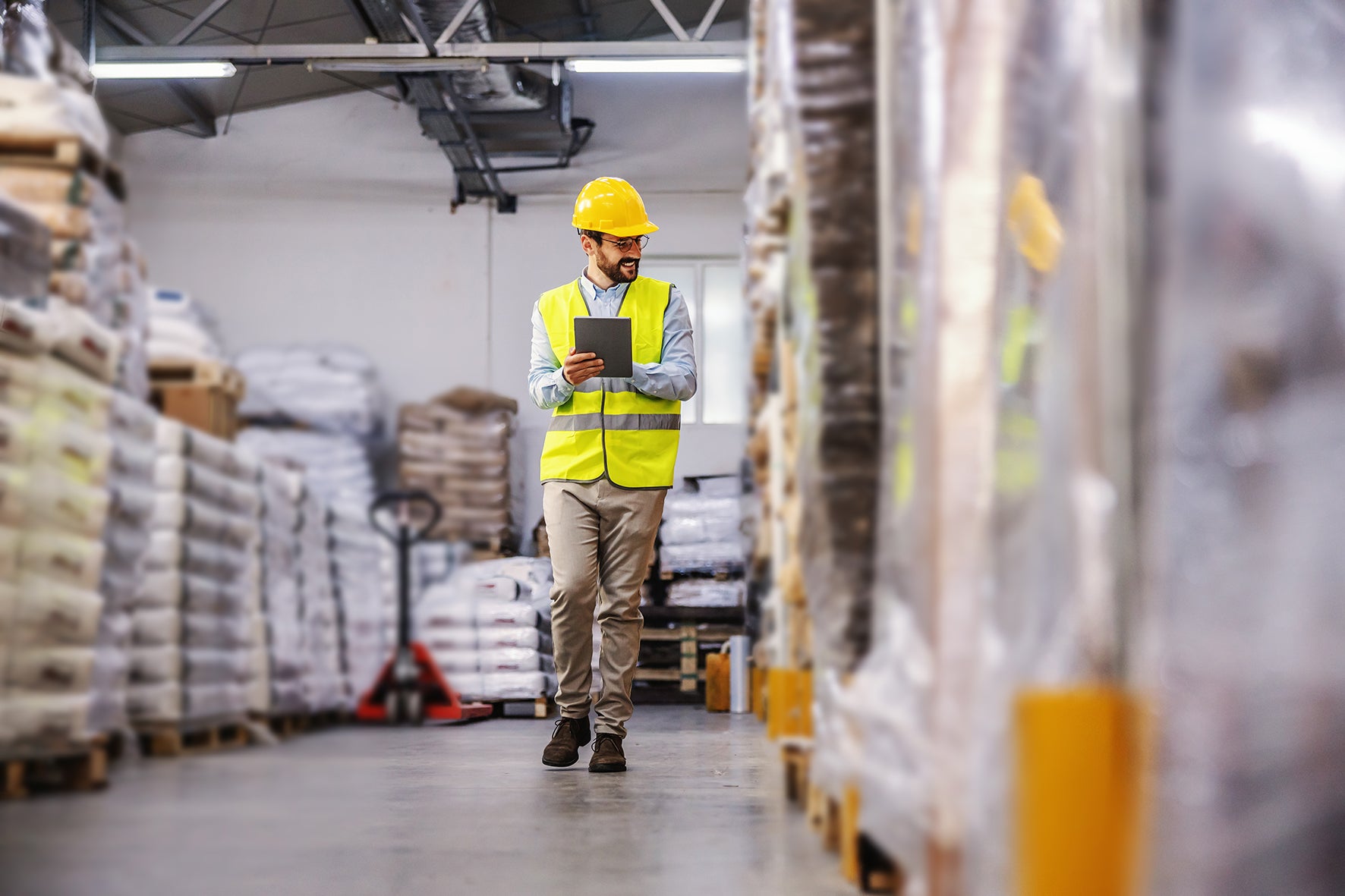 Warehouse with pallets and worker in a high vis with a clipboard.