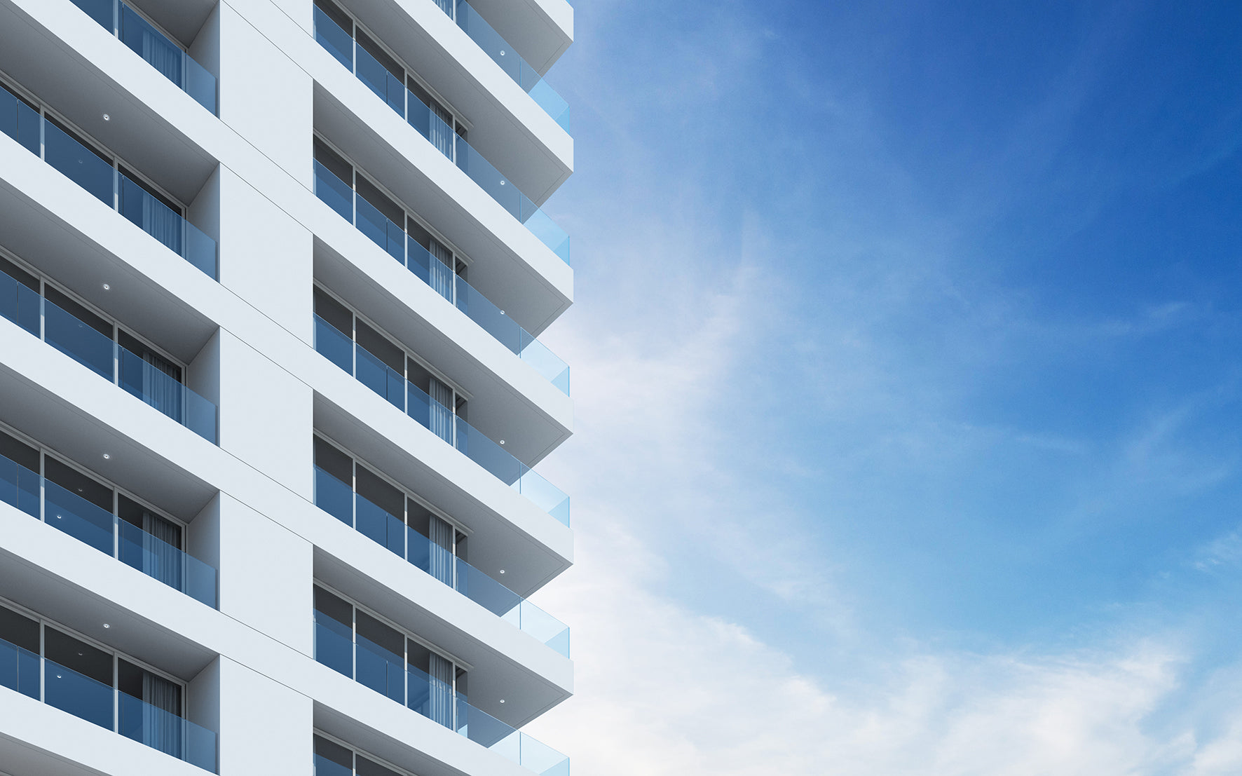 Modern white high-rise apartment building with glass balconies against a bright blue sky with light clouds.