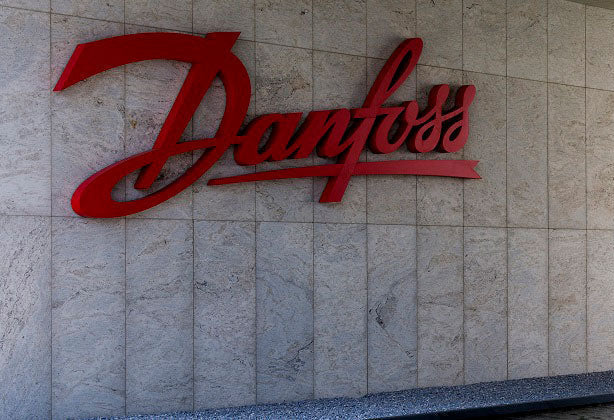Red 'Danfoss' logo on a stone wall